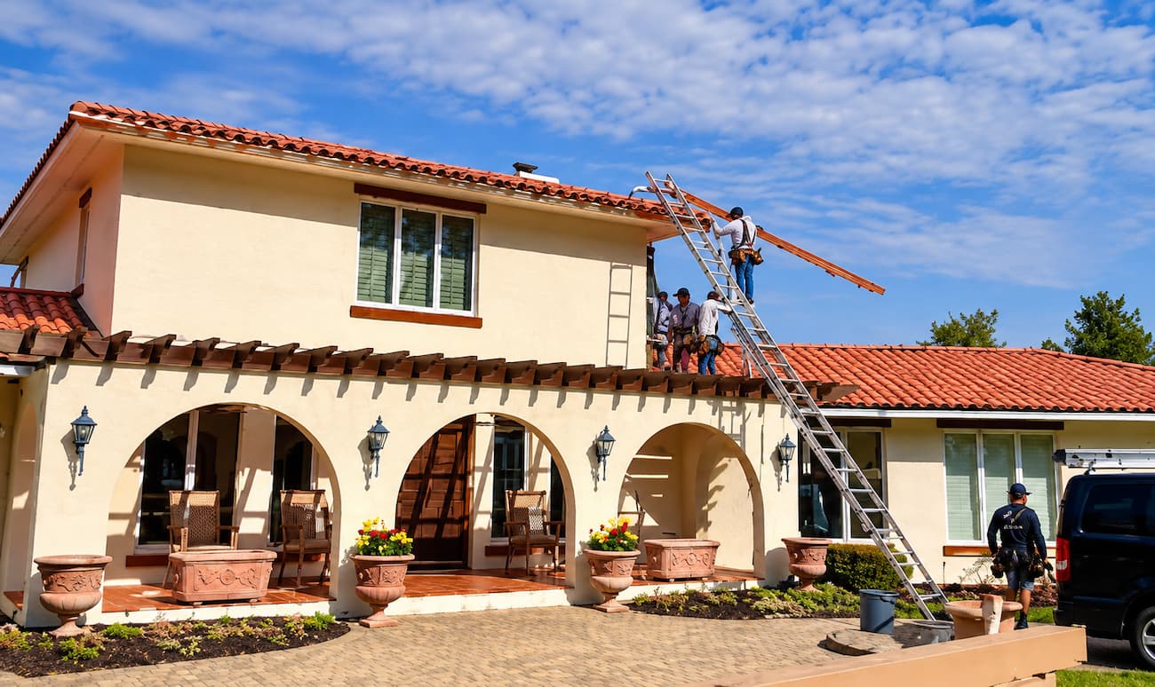 Red barrel tile roof, smooth stucco walls, and half-round copper gutters.